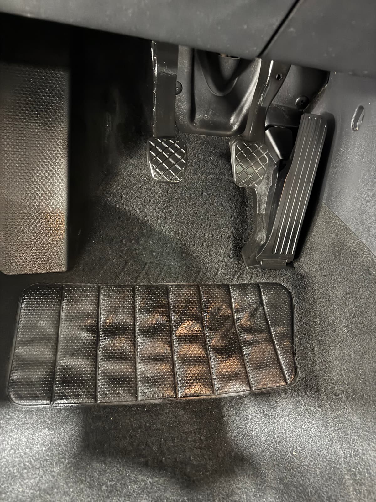 Spotless driver's footwell with clean carpet, fresh floor mat and polished pedals after professional interior detail at 2Clean Inc. Calgary